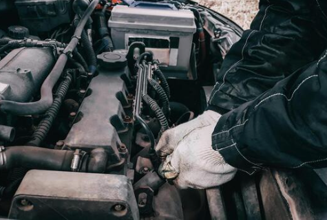 Mechanic inspecting engine components under the hood of a used vehicle