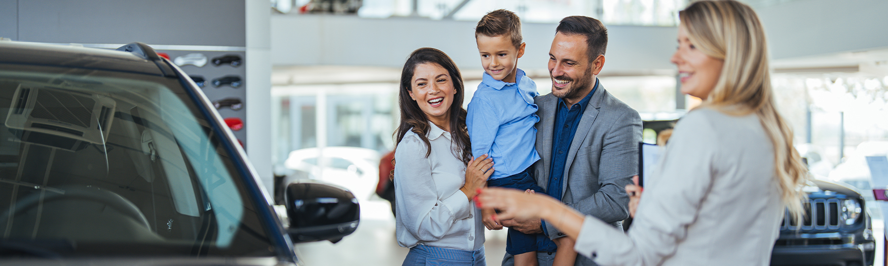 Dealership employee showing customers cars on showroom floor.