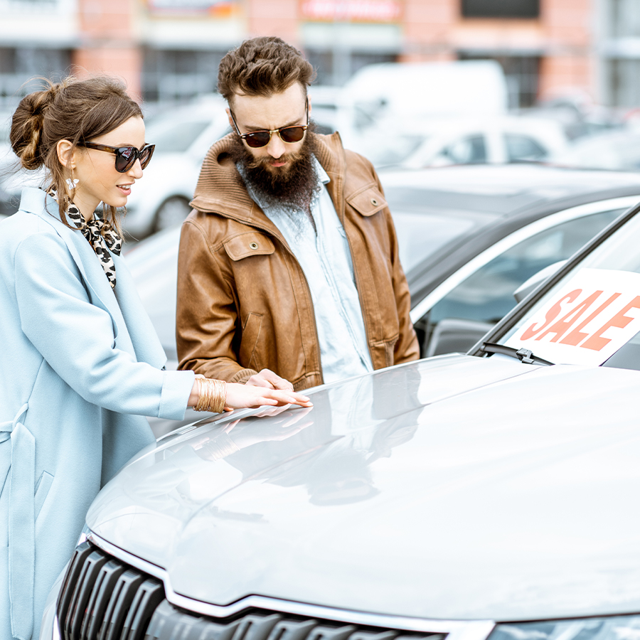 Couple with salesman discussing car purchase in showroom