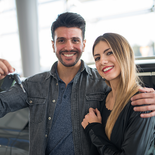 couple smiling with keys being held up