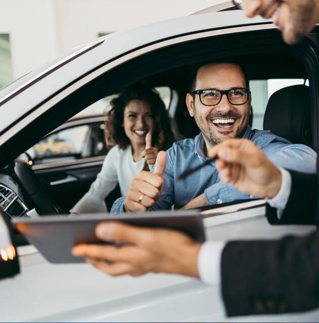 Smiling couple in car speaking to salesperson